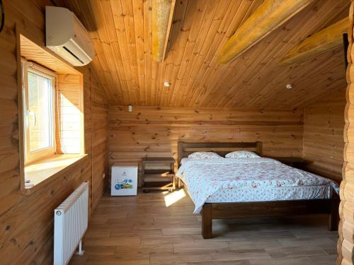 a bedroom with a bed in a wooden cabin at Міні-готель На Росі in Steblëv