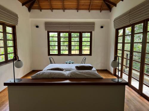 a bedroom with a large bed in a room with windows at Cinnamonhouse Villa in Poregedara