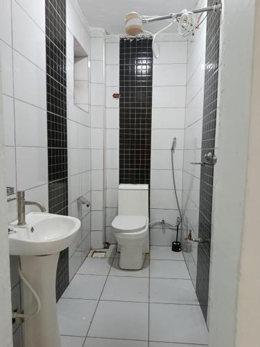 a white bathroom with a toilet and a sink at J & J Olosho Hotel in Kiserian