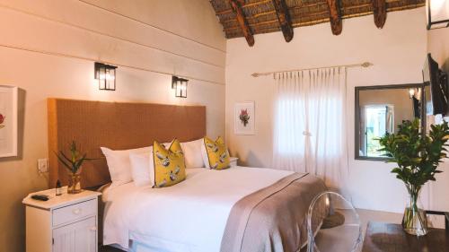a bedroom with a large white bed with yellow pillows at Onse Rus Guesthouse in Prince Albert