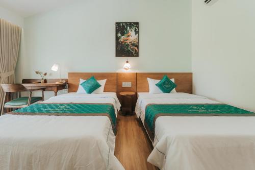 a hotel room with three beds and a table at November House in Thôn Kim Long (1)