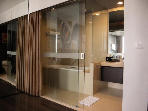 a glass shower in a bathroom with a sink at Akmani Hotel Jakarta in Jakarta