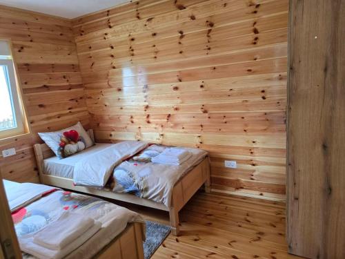 a bedroom with two beds in a wooden wall at Mountain House 22 in Žabljak