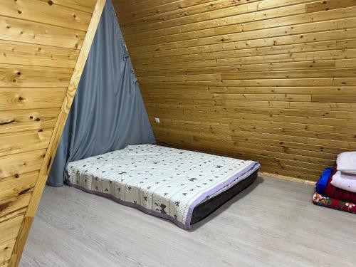 a bed in a room with a wooden wall at Esal Rest Zone in Tong