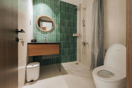 a green tiled bathroom with a toilet and a sink at November House in Thôn Kim Long (1)
