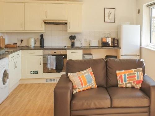 a living room with a brown couch in a kitchen at Ash Cottage in Uckfield