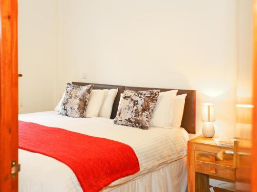 a bedroom with a large bed with a red blanket at Ash Cottage in Uckfield