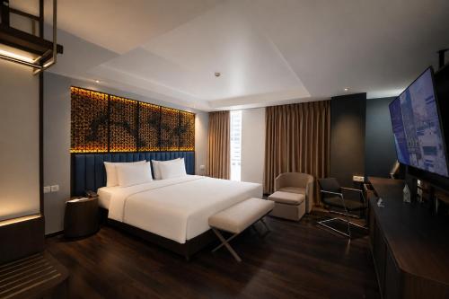 a hotel room with a bed and a television at Akmani Hotel Jakarta in Jakarta