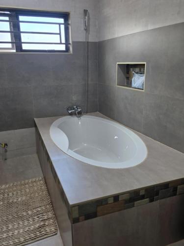 a large white tub in a bathroom with a window at Ednomis Apartment in Mazabuka