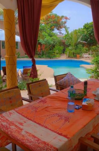a table and chairs with a table and a pool at Villa Symphonie Saly in Saly Portudal