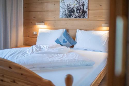 a bed with white sheets and pillows on it at Alpen Suite Apartment in San Vigilio Di Marebbe