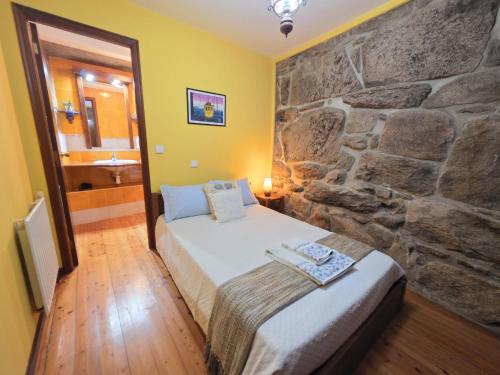 a bedroom with a bed and a stone wall at Villa Vetusta in Penso