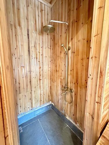 a bathroom with a shower in a wooden wall at Dốc Mơ Homestay in Bản Bé