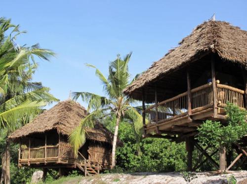 a resort with two huts and palm trees at Kitu Kiblu in Kilindoni