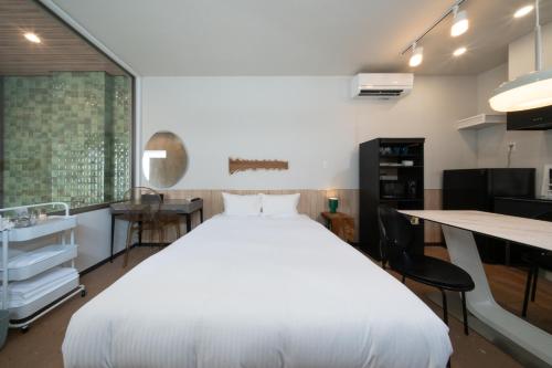 a bedroom with a large white bed and a desk at クリスタルパーク久松 in Miyako-jima