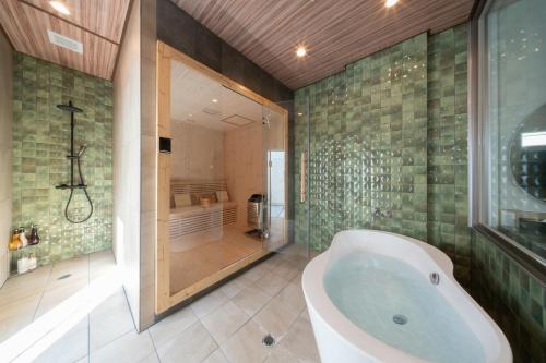 a bathroom with a tub and a walk in shower at クリスタルパーク久松 in Miyako-jima