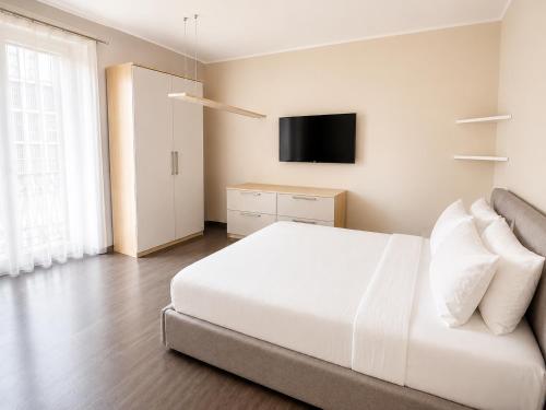 a bedroom with a white bed and a flat screen tv at Porta Nuova Studio - Sostify in Bergamo