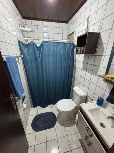 a bathroom with a toilet and a blue shower curtain at Cantinho Muriu in Ceará-Mirim