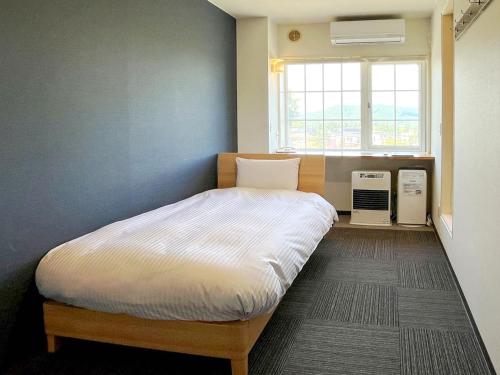 a bedroom with a bed in a room with a window at CHALET BURLAP FURANUI in Furano