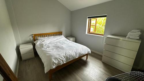 a bedroom with a bed and a dresser and a window at Peacock Barn in Walsoken