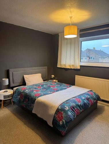 a bedroom with a bed with a colorful blanket and a window at Unnati stay in Buckinghamshire