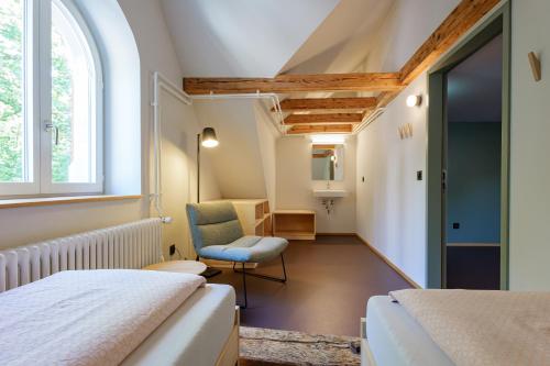 a bedroom with two beds and a chair and a window at Schaffhausen Youth Hostel in Schaffhausen