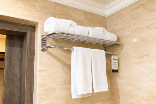 a bathroom with white towels on a towel rack at Metro Park View Hotel Kota Lama Semarang in Semarang
