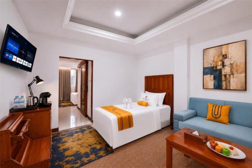 a hotel room with a bed and a blue couch at Metro Park View Hotel Kota Lama Semarang in Semarang