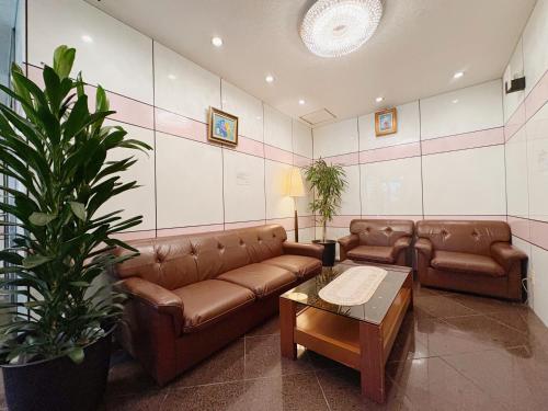a living room with brown leather couches and a table at Weekly Green In Namba in Osaka