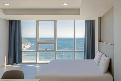 a bedroom with a bed and a large window at Sun Cloud Hotel in Busan