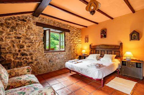 a bedroom with a bed and a stone wall at La Casa de Torre in Ribadesella