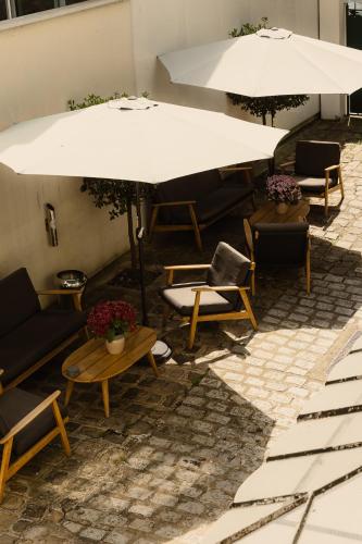 a patio with tables and chairs and an umbrella at Hôtel Helzear Montparnasse by Esteem in Paris