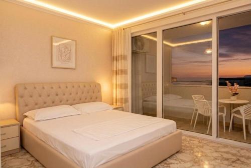 a bedroom with a bed and a balcony with a table at Leonard's Shengjin Apartments in Lezhë