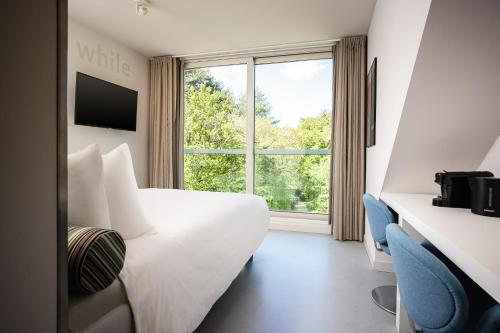 een hotelkamer met een wit bed en een raam bij blooming in Bergen