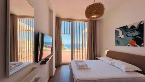 a bedroom with a bed and a large window at Veranda Apartment, Green Coast in Palasë
