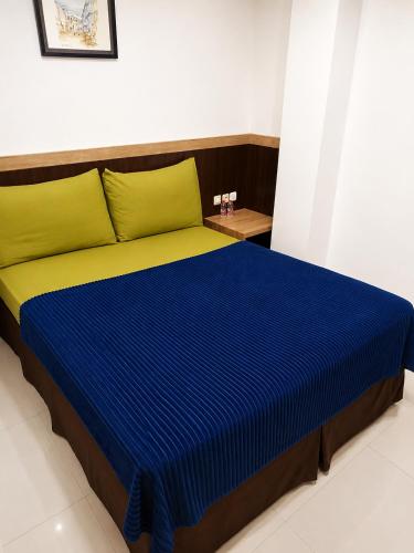 a bedroom with a bed with blue and yellow sheets at Grand Kalimas Hotel in Surabaya