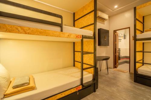 a room with three bunk beds and a desk at Cafe Moto Hostel in Puerto Princesa City