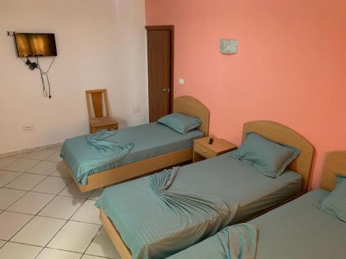three beds in a room with orange walls at Montazah Residence in Dar el Koudia