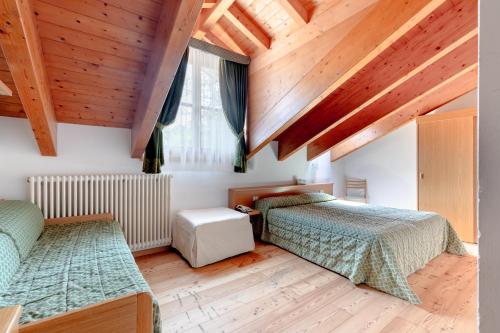 a bedroom with two beds and wooden ceilings at Garni Lago Nembia in San Lorenzo in Banale