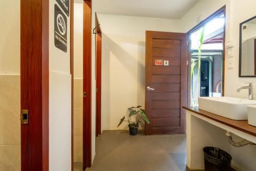 a bathroom with a sink and a mirror and a door at Cafe Moto Hostel in Puerto Princesa City