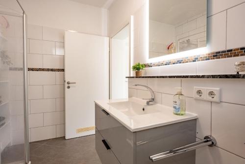 a white bathroom with a sink and a shower at Plätzchen im Grünen in Owingen
