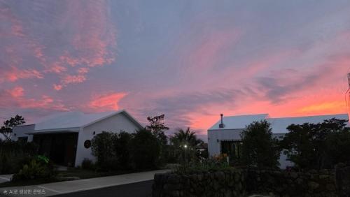 a house with a sunset in the sky at Jeju Gallery House in Jeju