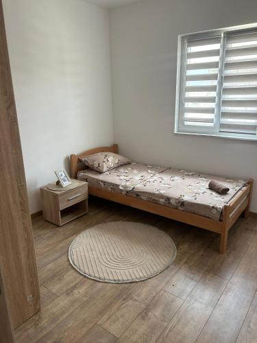 a bed in a room with a window and a rug at Apartman Šarenac in Bileća