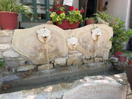 a fountain with two lion heads on a stone bench at Arena's nest in Áyioi Dhéka