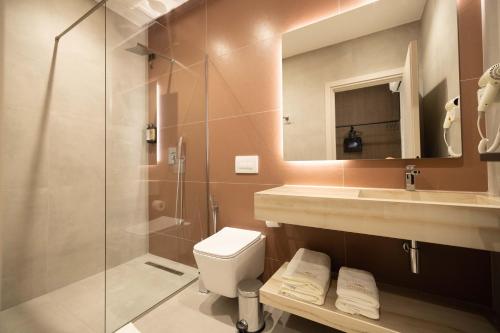 a bathroom with a shower and a toilet and a sink at Hotel Digreis in Vlorë