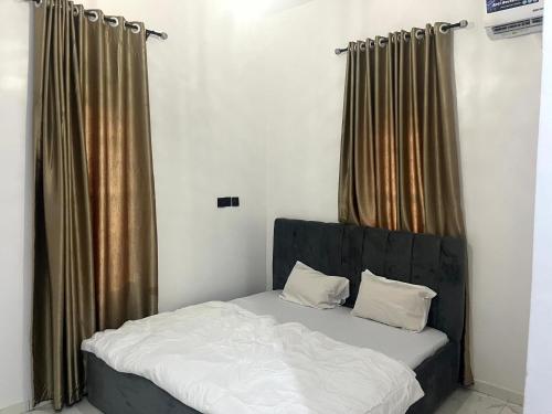 a bed with a black headboard in a room with curtains at Universal Apartment & Suites in Ibadan