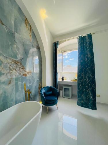 a bathroom with a tub and a blue chair at Zagara Suite in Francofonte