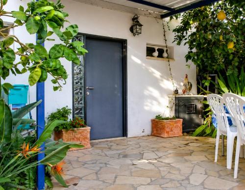 a patio with a blue door and white chairs at נופש דביר - צימרים מהממים למשפחות עם ג'קוזי ובריכה ליד הכנרת in Migdal