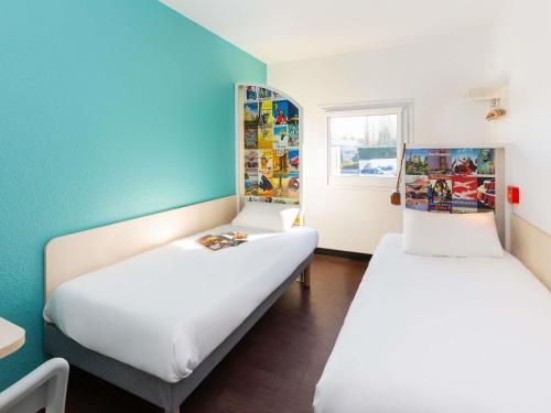 two beds in a room with blue walls at hotelF1 Longwy in Longwy