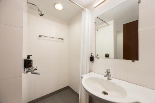 a white bathroom with a sink and a shower at Ginger Pantnagar in Pantnagar
